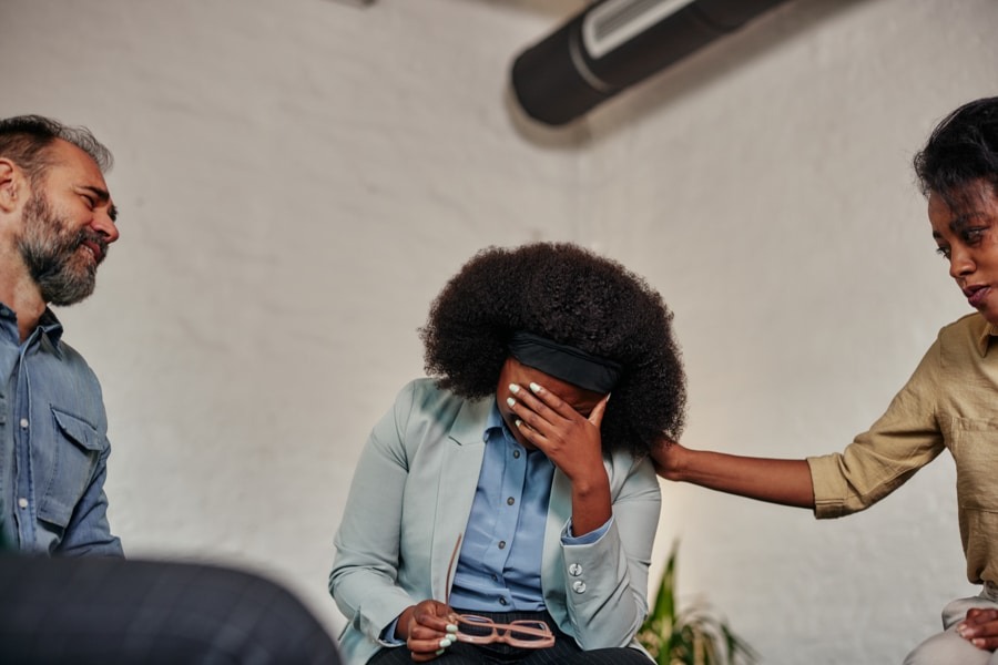 chronic-pain a woman with her hand on forehead while being comforted